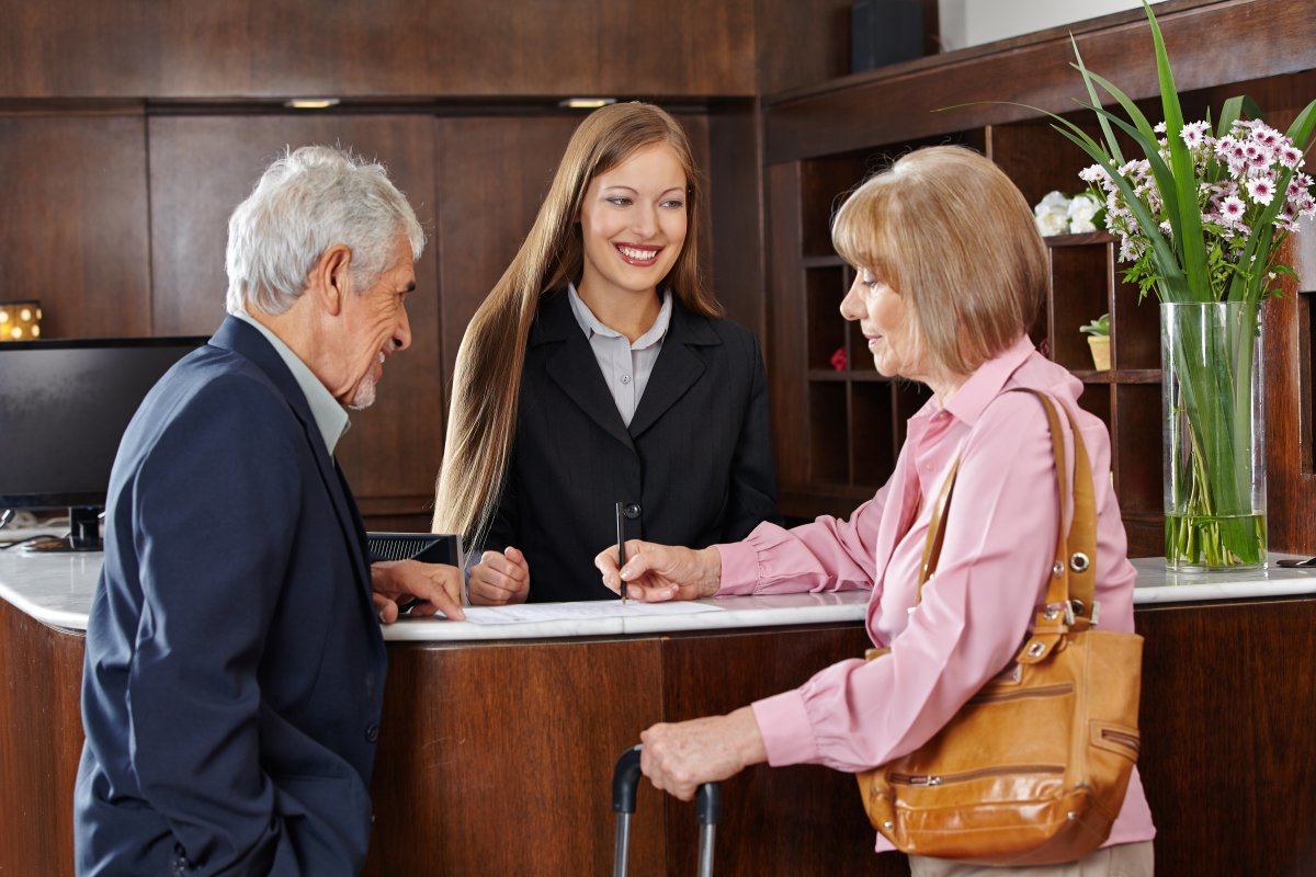Senior Couple In Hotel Signing Form