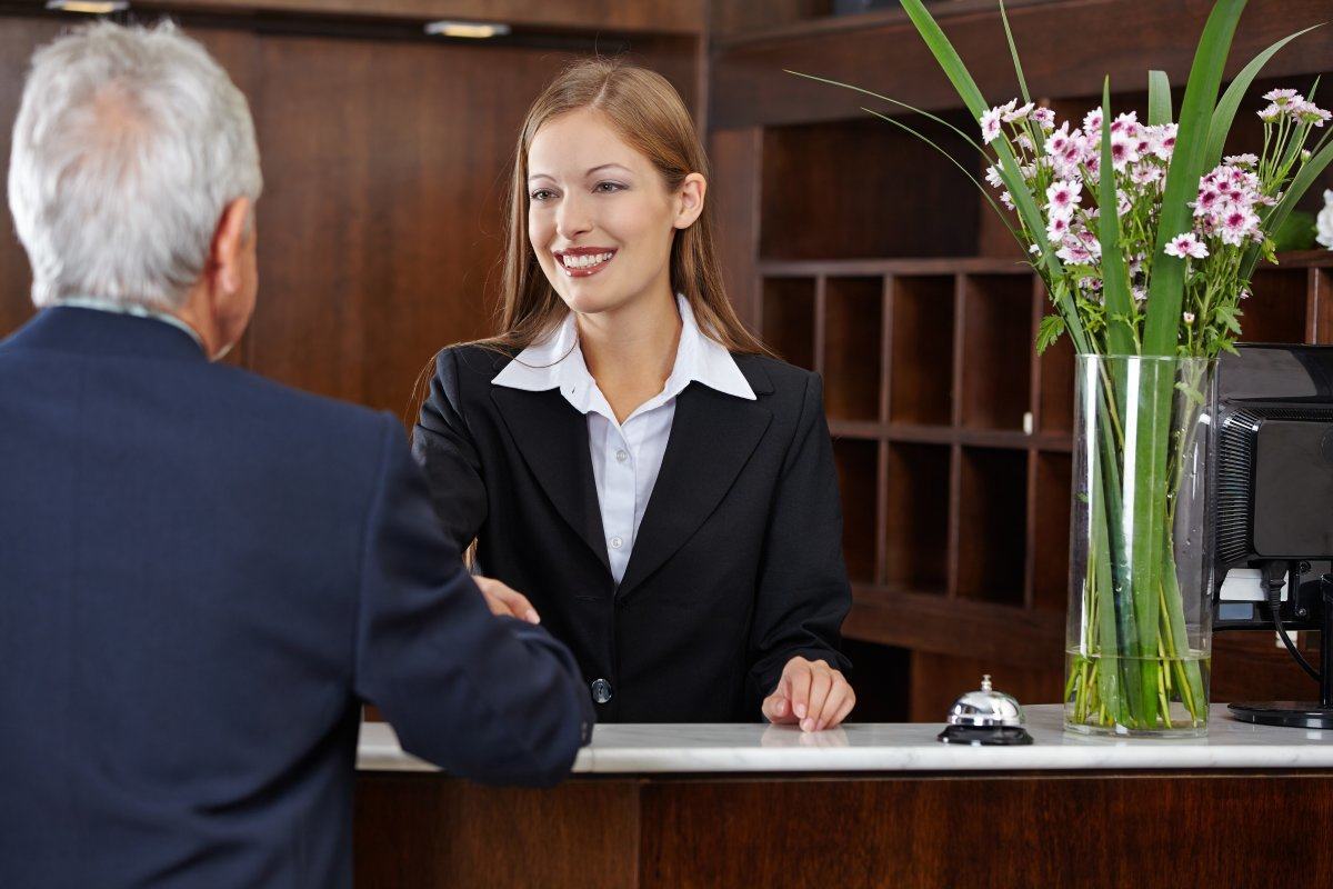 Smiling Female Receptionist Greeting A Senior Guest