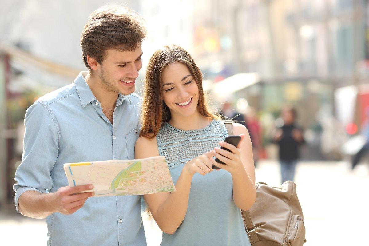 Tourists Consulting A City Guide And Smartphone GPS