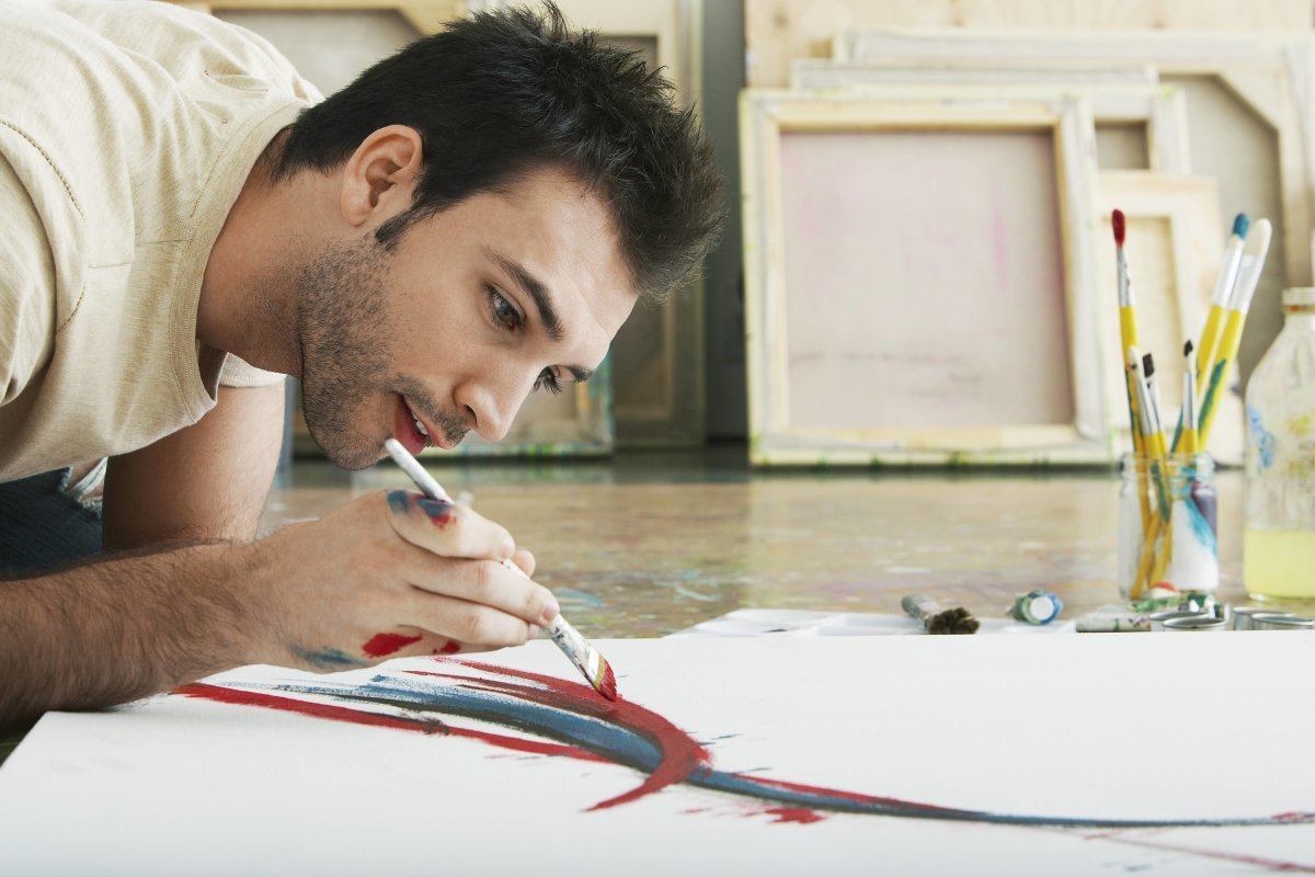Young Man Painting On Canvas On Studio Floor
