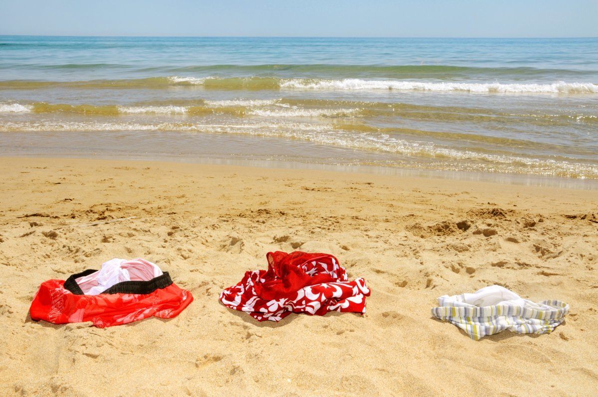 Some Swimsuits Laying On The Sand Of A Beach