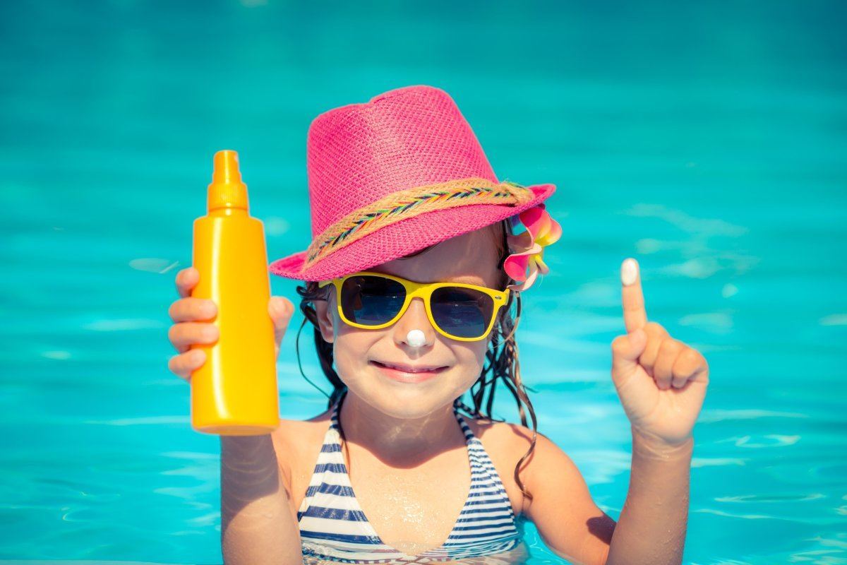 Happy Child Holding Sunscreen Lotion