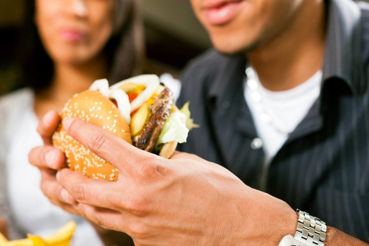Happy Man Eating A Hamburger With His Girlfriend