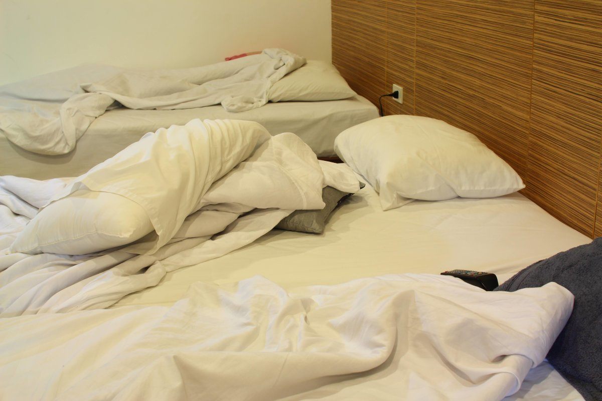 Interior Shot Of Motel Room With Unmade Bed