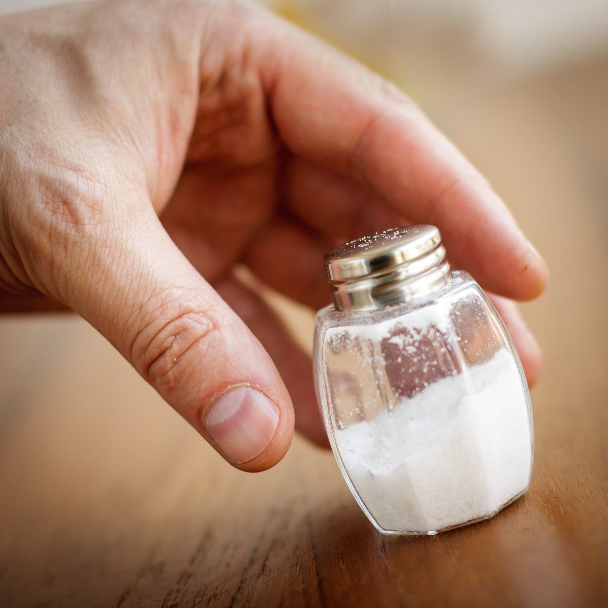 Salt Shaker Taken By Hand From Wooden Table