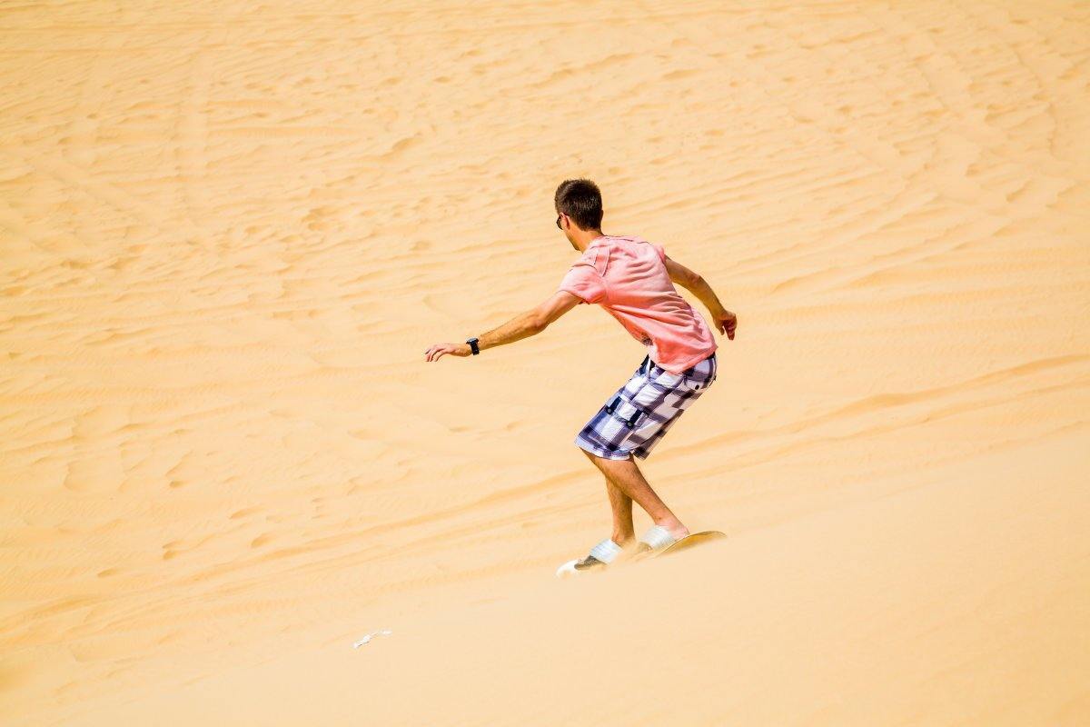 Sand Boarding Down The Dune In A Desert Near Emirates