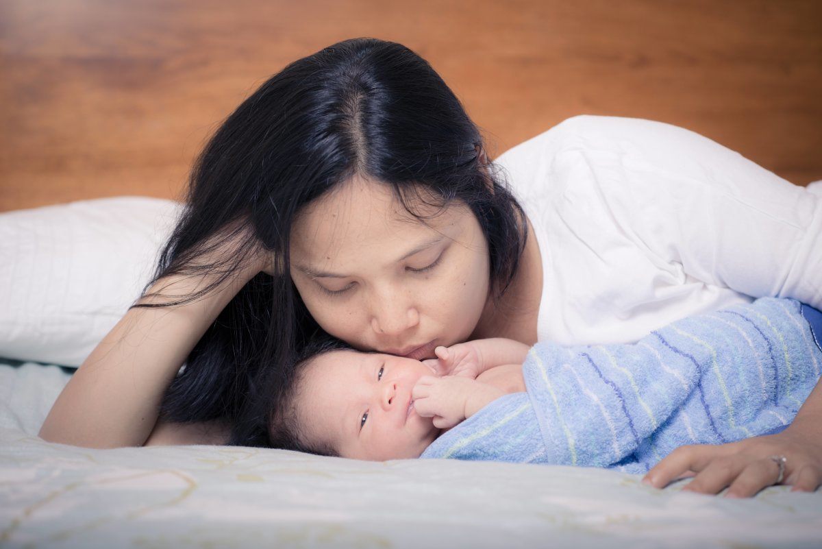 Asian Mother Lays On Her Bed with Baby