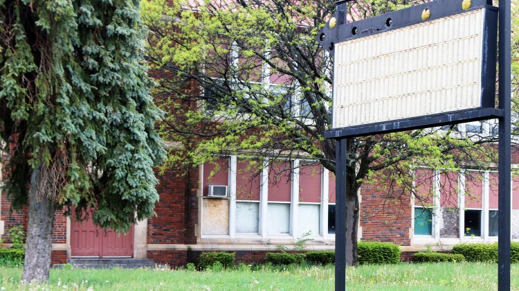 Blank Sign In Front Of An Abandoned Building.