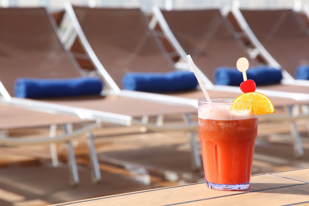 Cocktail With Fruits In Glass On Rail Near Beach Armchair In Cruise Liner