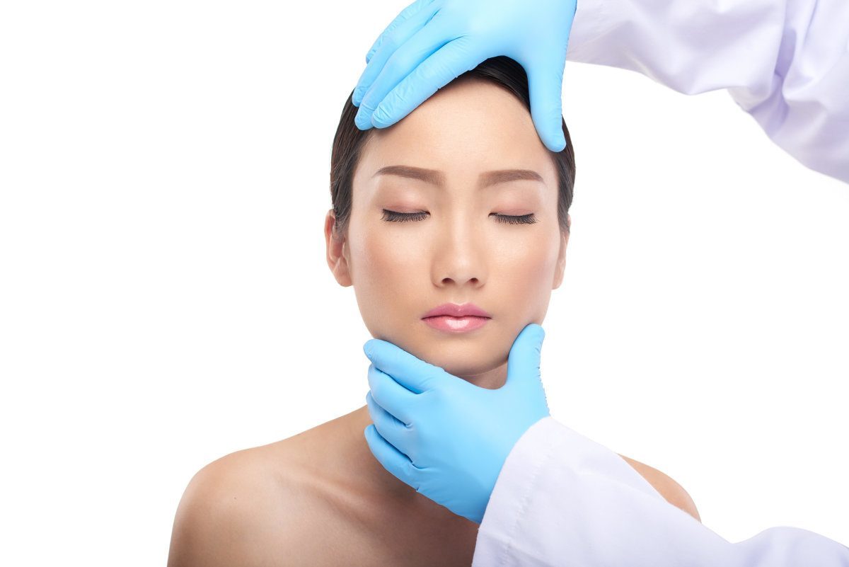Doctor Examining Facial Skin Of Beautiful Young Woman