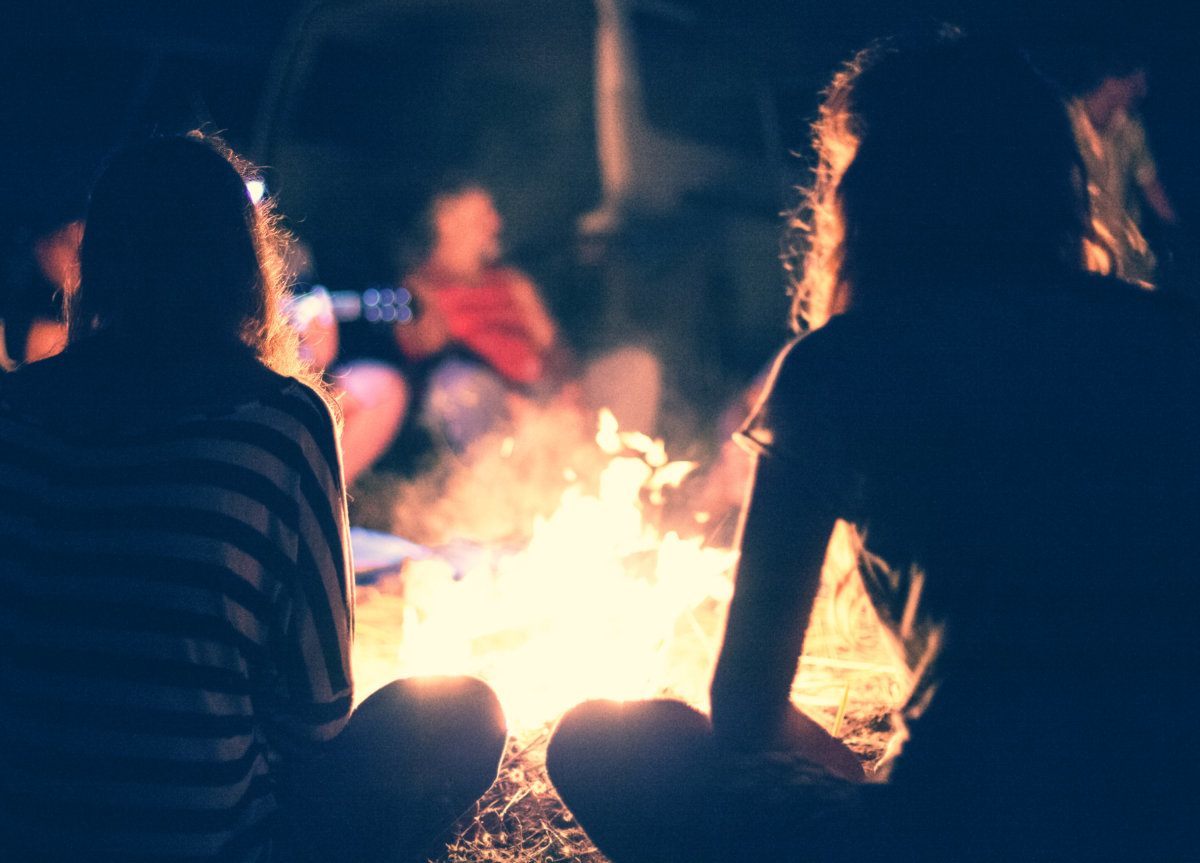 People Sit Around A Bright Bonfire