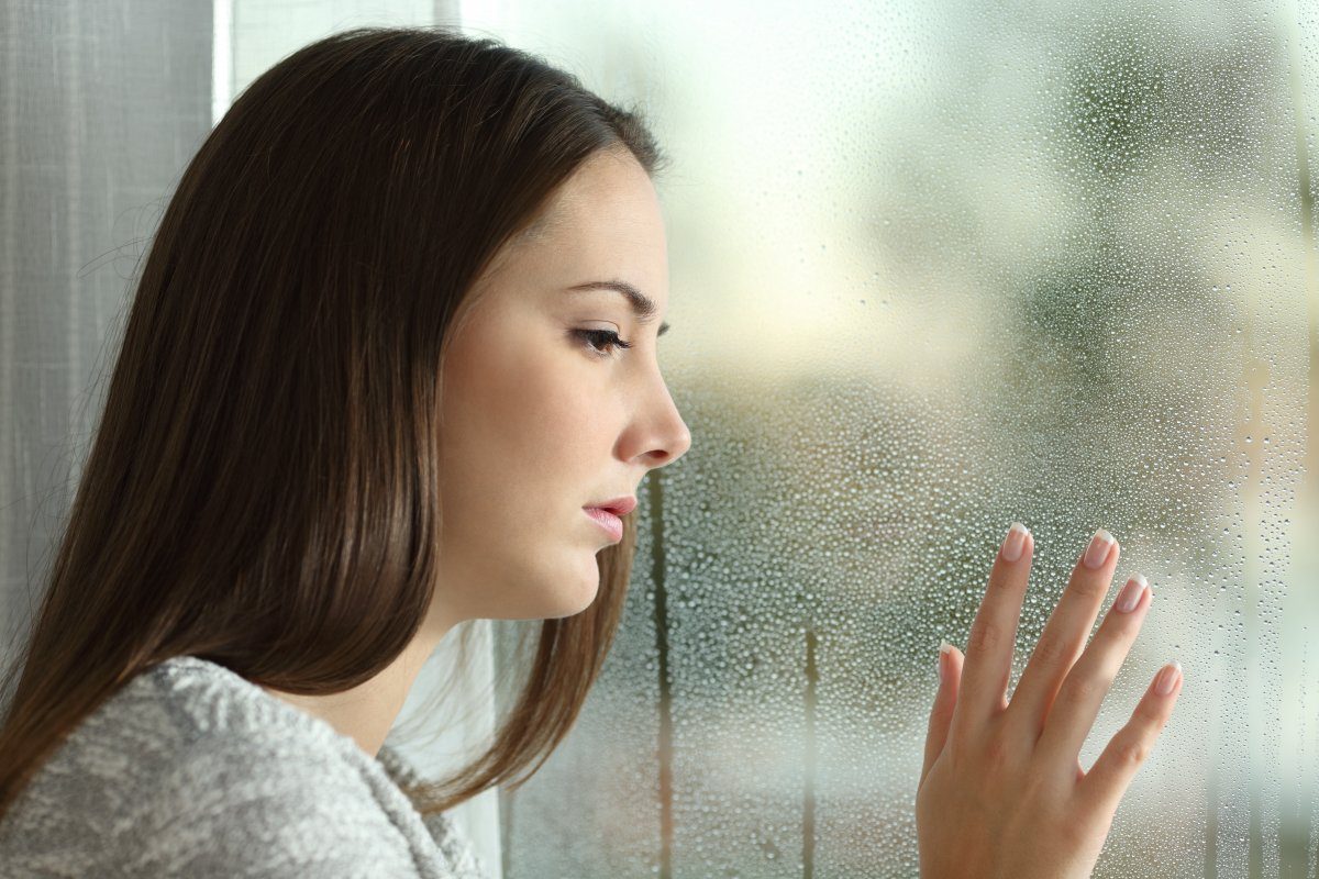 Sad Woman Looking Through A Window At Hotel