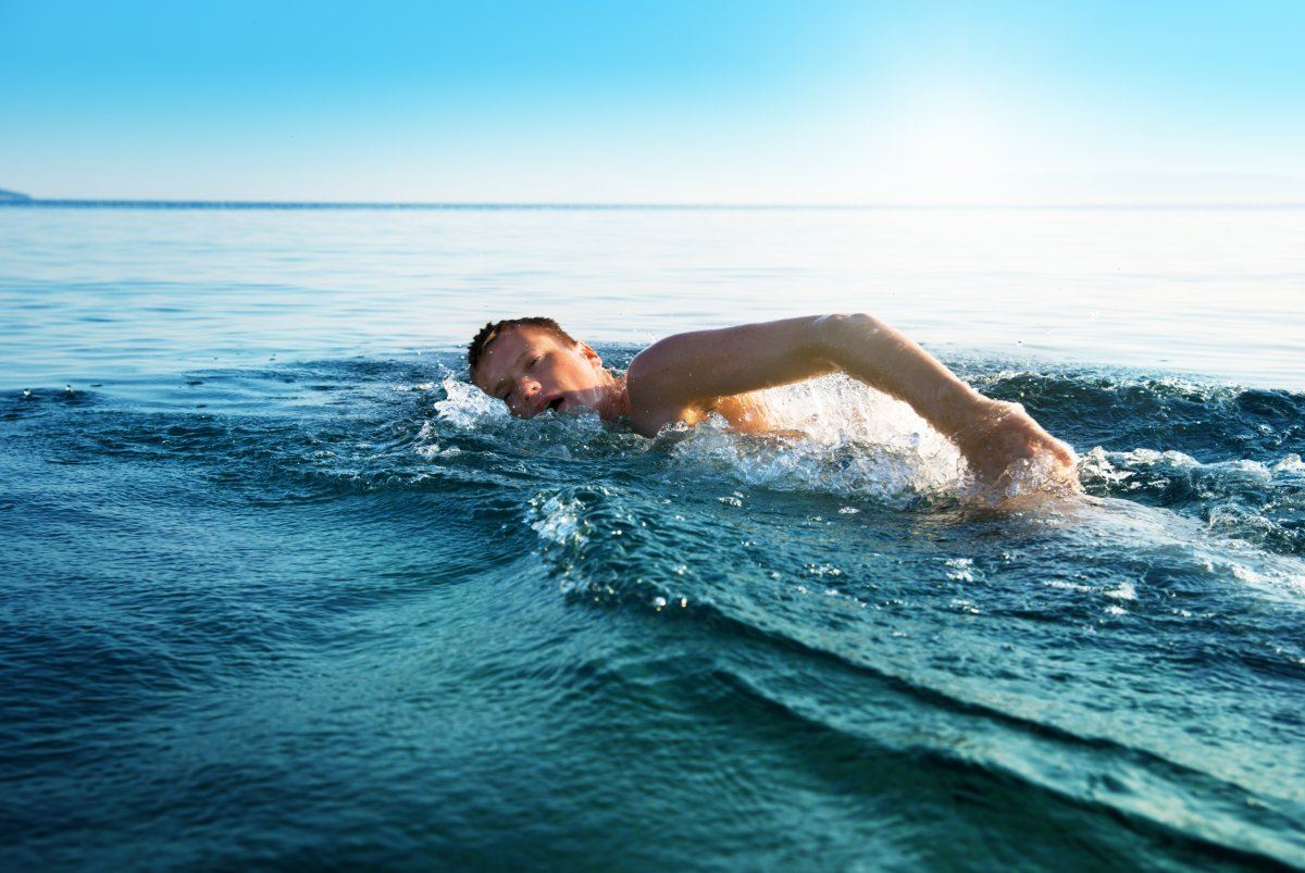 Young Man Swimming In Oceans Water