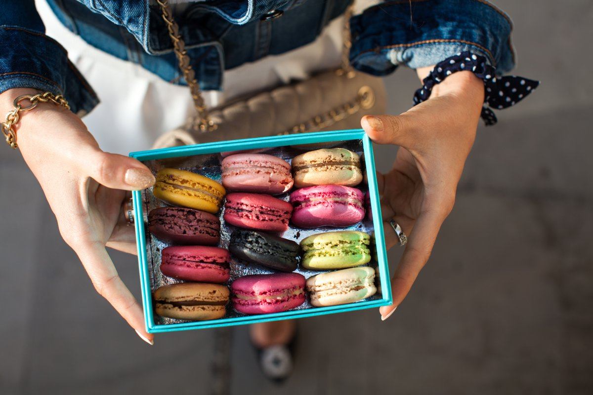 Woman holding box with colourful macaroons. Dessert. Summer travel vacation in French Riviera