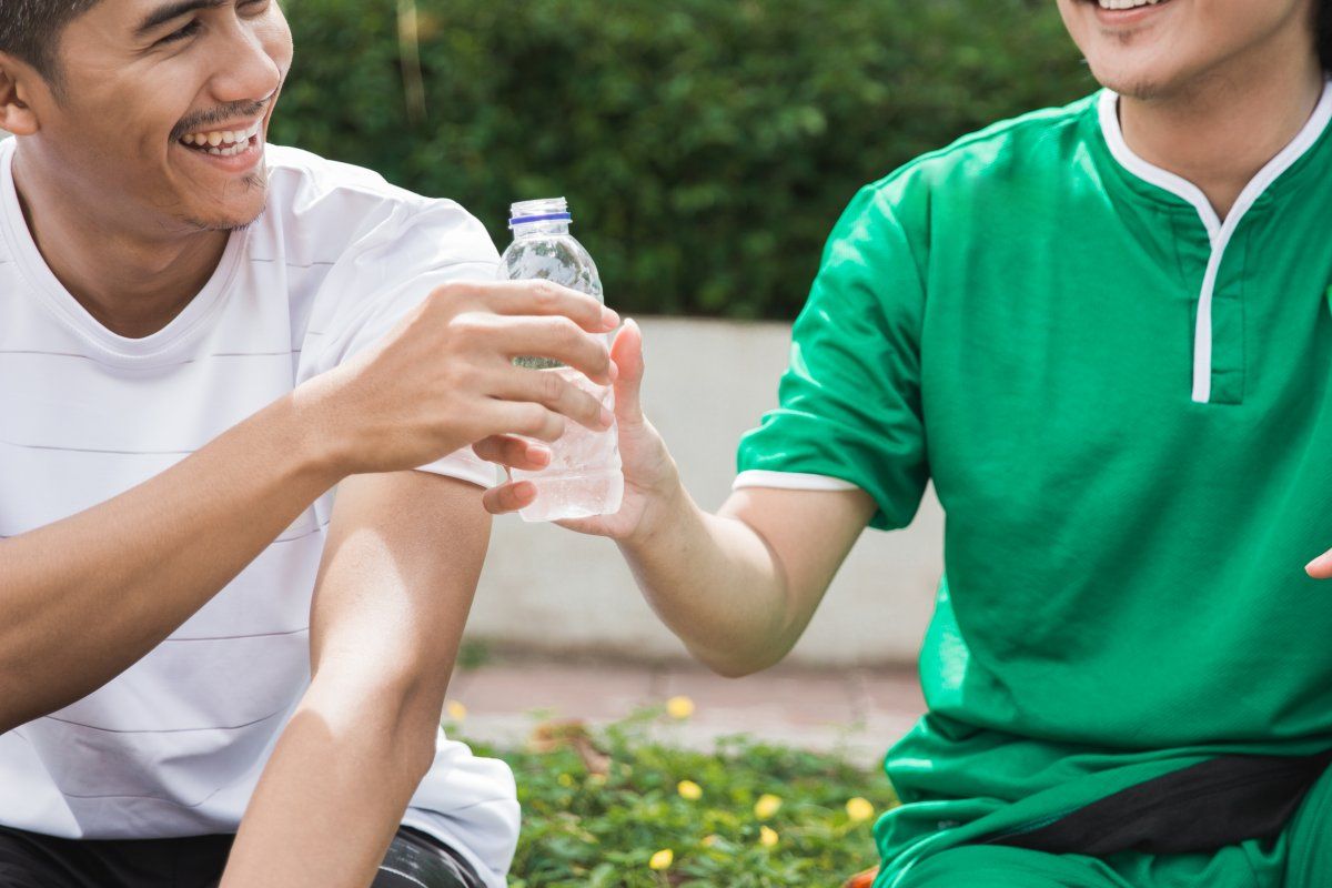 friend giving or sharing water bottle after exercising