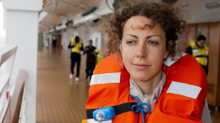 girl in life jacket on ship with other people